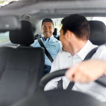 Middle-aged passenger speaking with a professional Eurotaxis driver inside a comfortable vehicle, demonstrating friendly customer service and reliable local taxi transport.